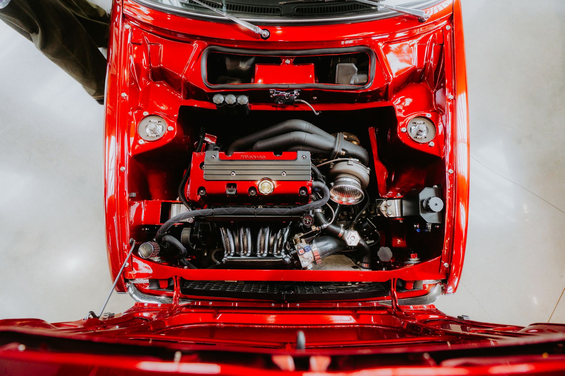 Top-down view of a car engine in a vividly red automobile, showcasing detailed components.