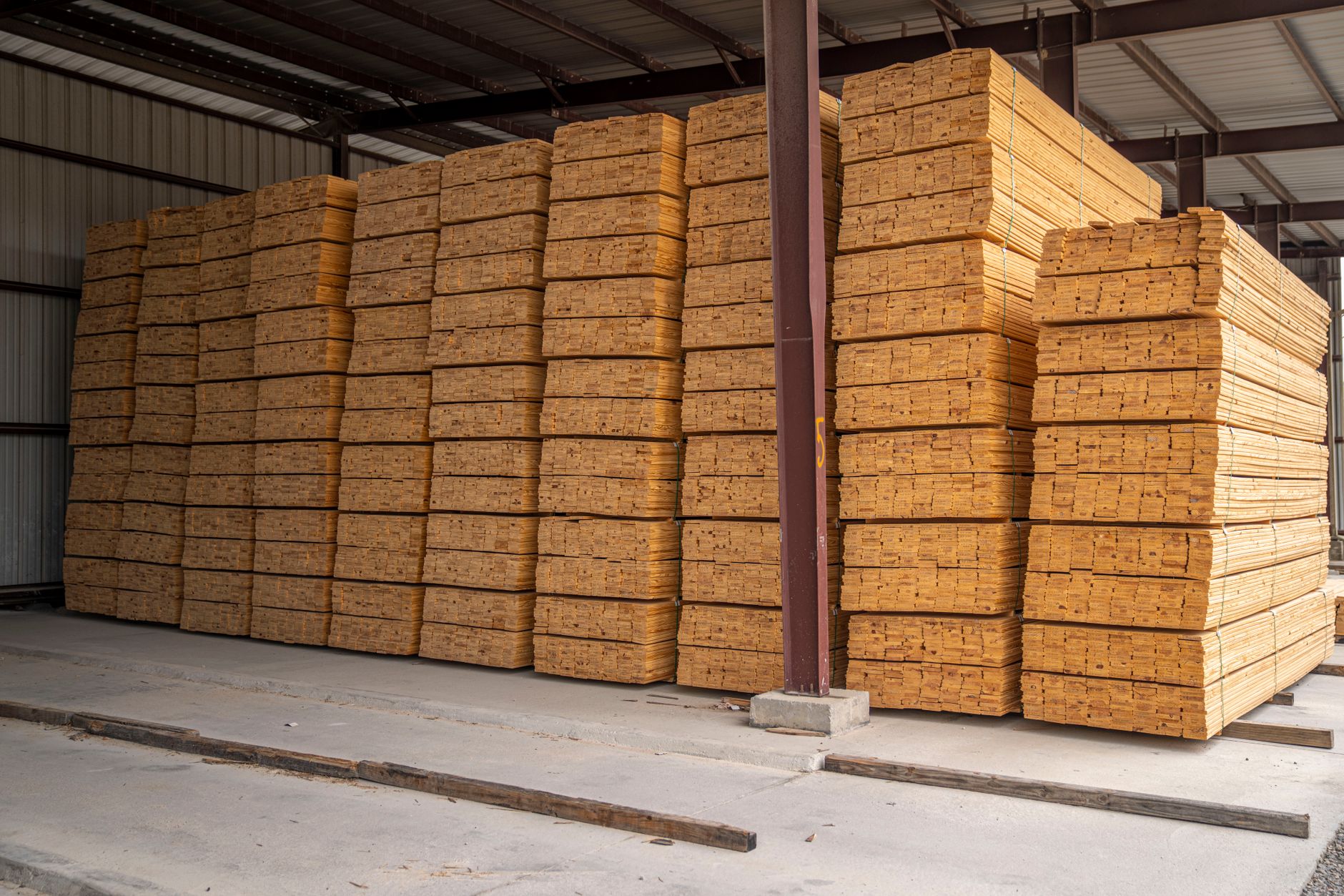 Large stacks of neatly arranged wood planks in an industrial storage facility.