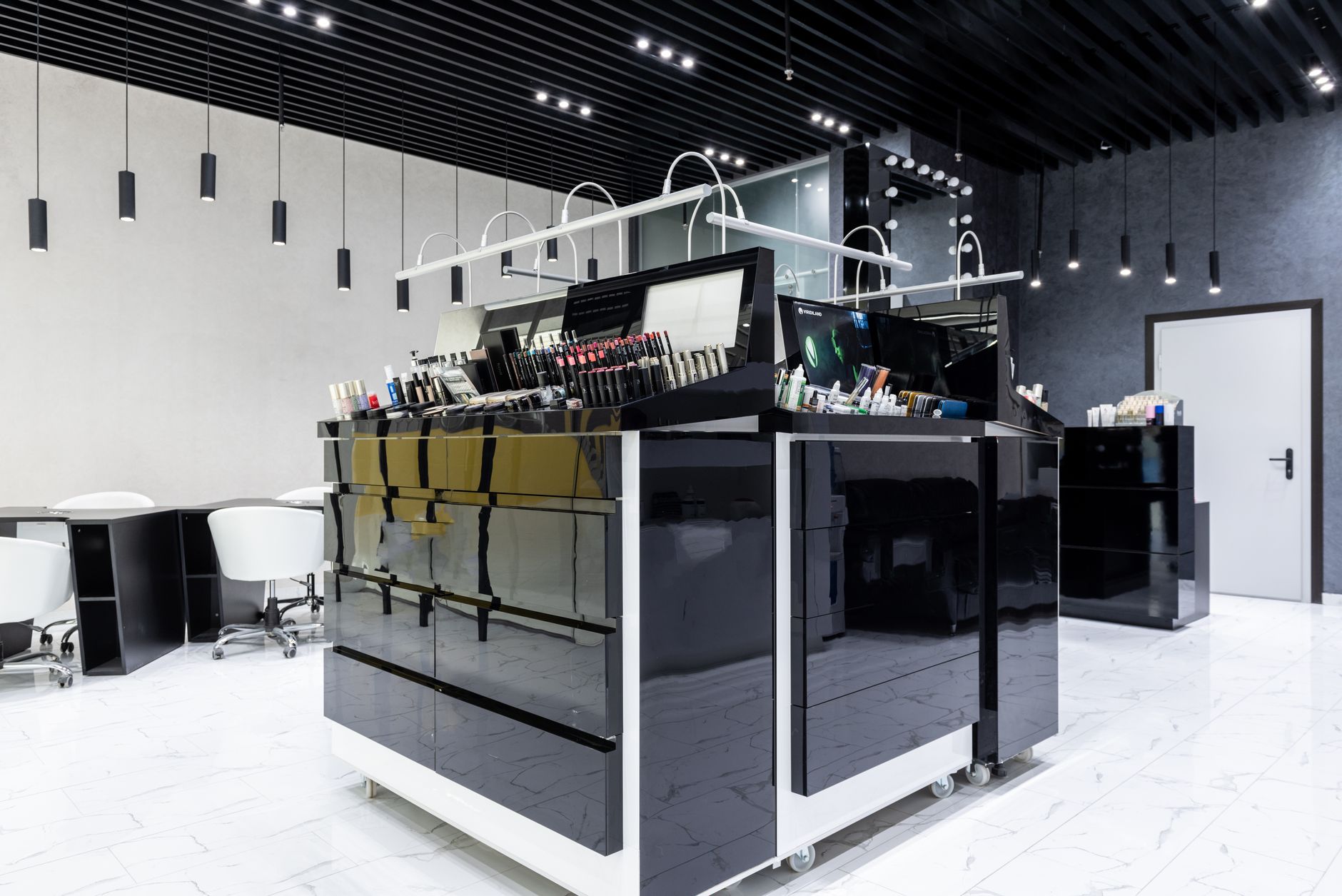 Sleek makeup store interior featuring black glossy cabinets, chairs, and ample lighting.